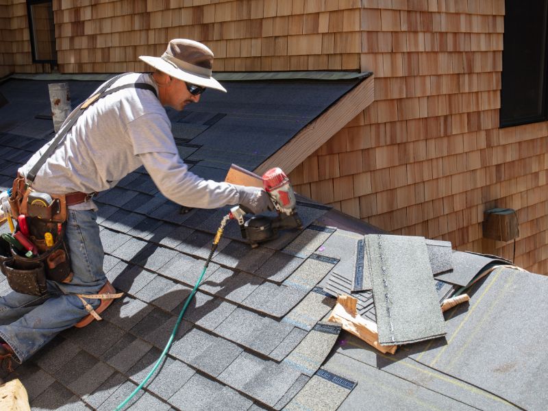 a man repairing the shingles on a roof